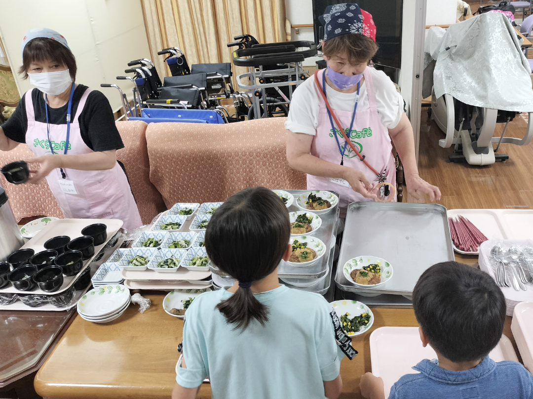 地域の方が子供とコミュニケーションをとりながら食事を配っていく写真