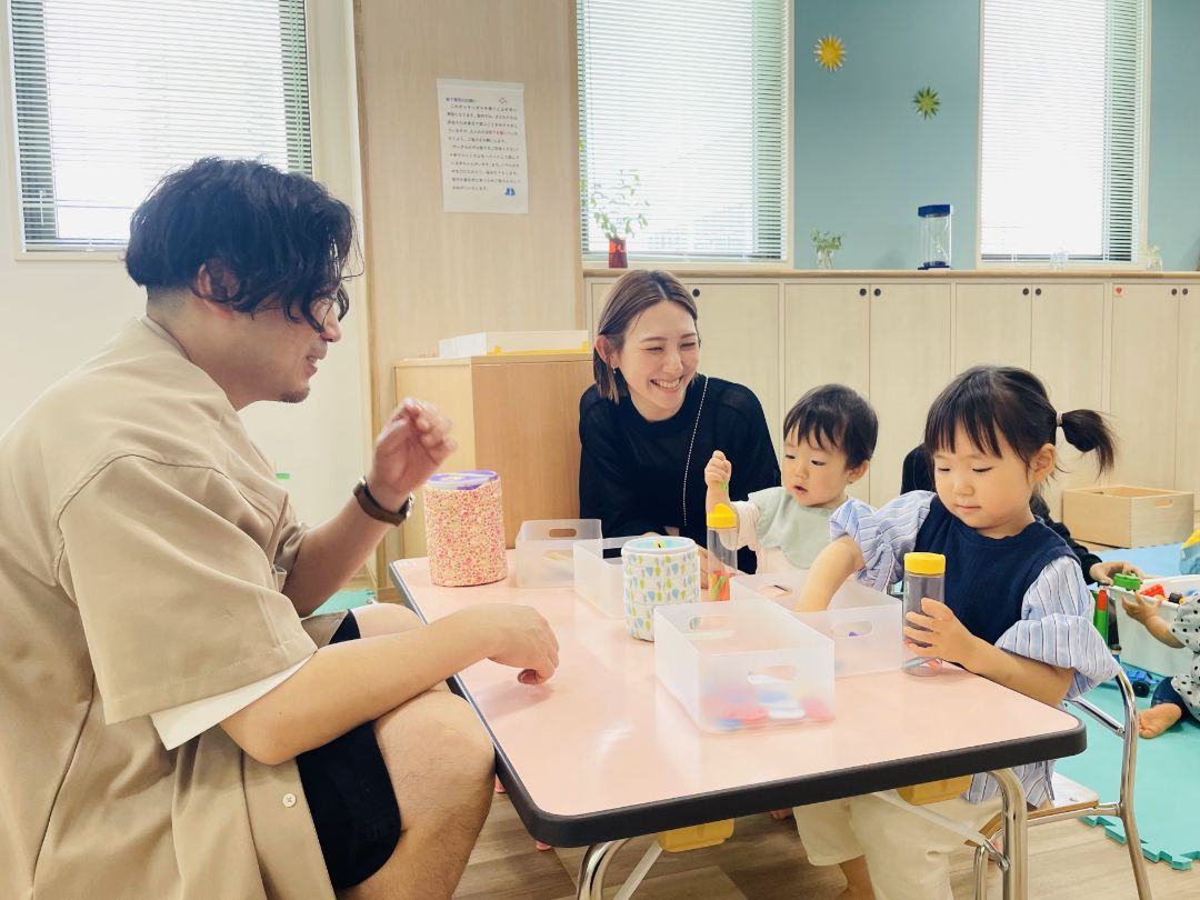 保育士さんと子供たちがおもちゃで遊んでいる写真