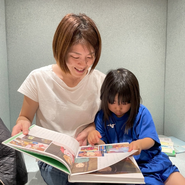 図鑑を読んでいるお母さんと子供の写真