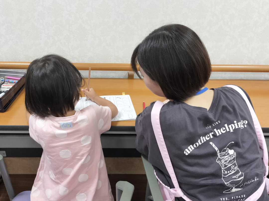 大学生と子供が話している背中越しの写真