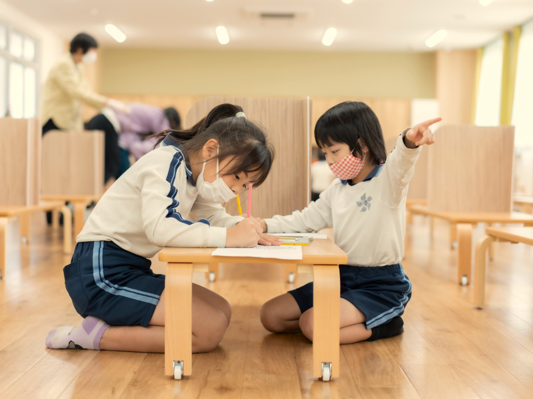 二人の子供がテーブルを挟んで懸命に学習している写真