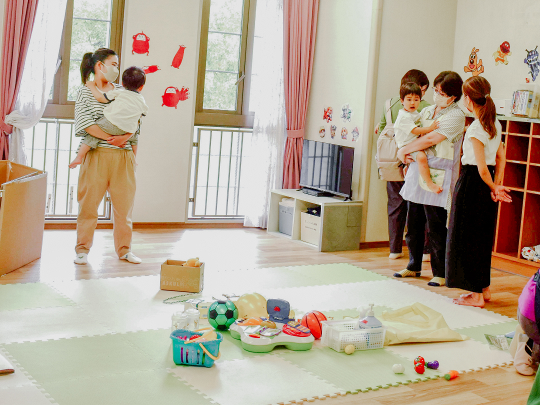 保育ルームで子供をあやす保育士さんとお母さんの写真