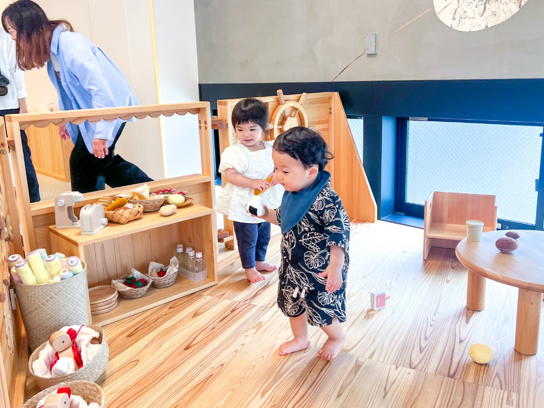 木材を使用したおもちゃや床で構成されているスペースで子供が遊んでいる写真