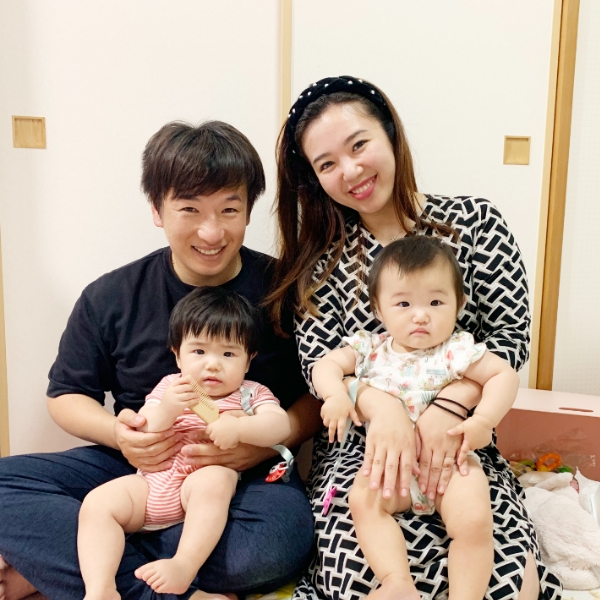 双子を膝に抱える夫婦の写真