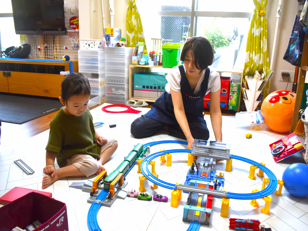 電車のおもちゃでヘルパーと遊んでいる子供の写真