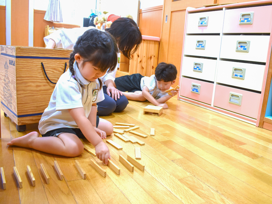 床に積み木を並べて遊んでいる子供の写真