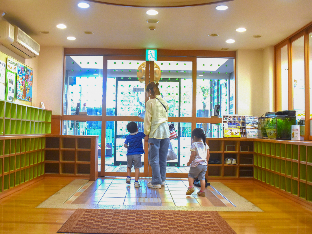 保育園入口から出るお母さんと子供たちの写真