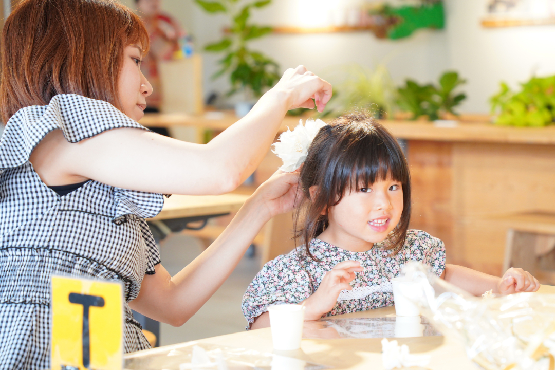 和紙の花で作成した髪飾りを子供につけるお母さんの写真