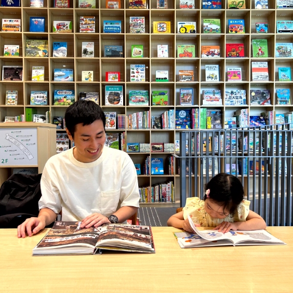 3歳の子供と、お父さんがデスクで本を読んでいる写真