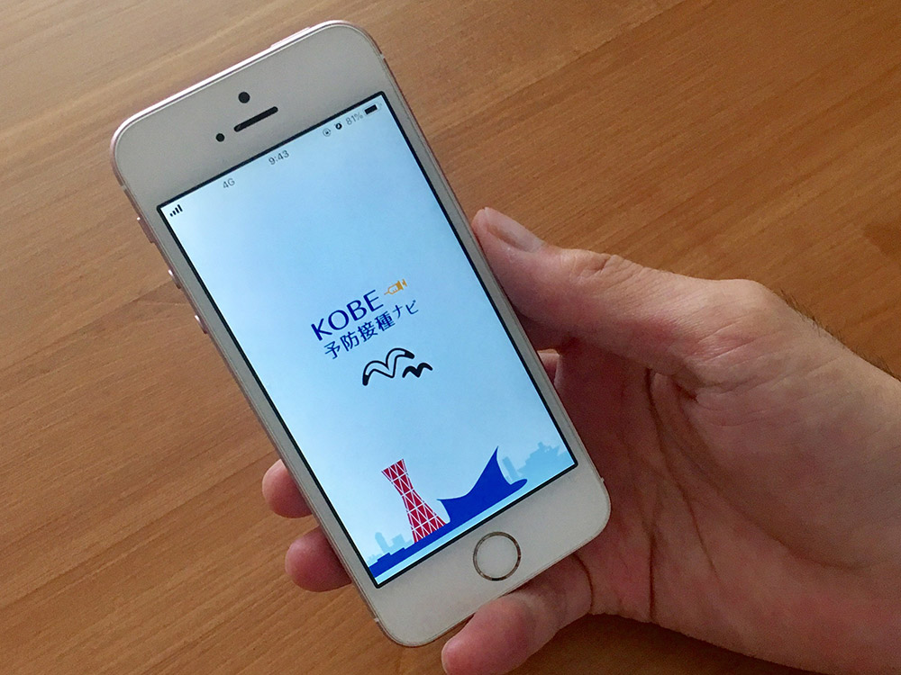 スマートフォンでKOBE予防接種ナビのアプリ画面を開いている手もとの写真